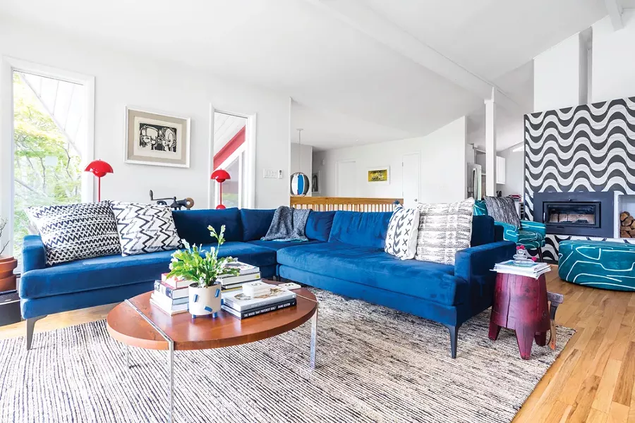 A lounge in the living room was carefully planned to take full advantage of the river - views and then decorated with an eclectic mix of colors and textures. “I’m always - trying to throw curveballs,” says Schultz about her design ethos. “I look for the - dynamic between people and then figure out ways to implement their particular - character into their family areas.” The block print featured on the wall is a particular - favorite. Titled Two Little Boys, it was created by civil rights lawyer R. Livingston. - PHOTO BY WINONA BARTON-BALLENTINE