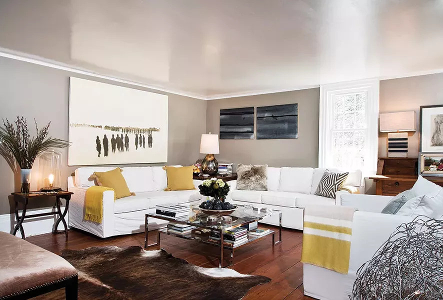 The home's living room has original wide-plank wooden floors and a fireplace, and is decorated with pillows and a throw blanket woven from alpaca fur. - DEBORAH DEGRAFFENREID