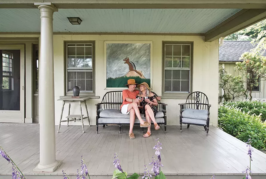 Valerie Shaff and Stephen Kingsley enjoying their front porch. Behind them hangs a painting of a chipmunk by outsider artist Earl Swanigan. - DEBORAH DEGRAFFENREID