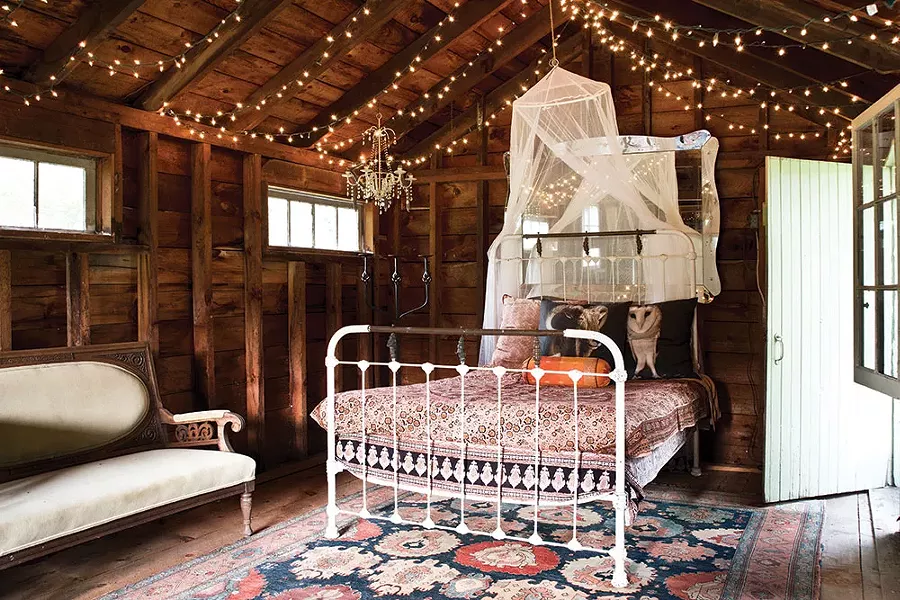 An iron bed in the outbuilding is decorated with Shaff’s owl portraits printed on pillows. - DEBORAH DEGRAFFENREID