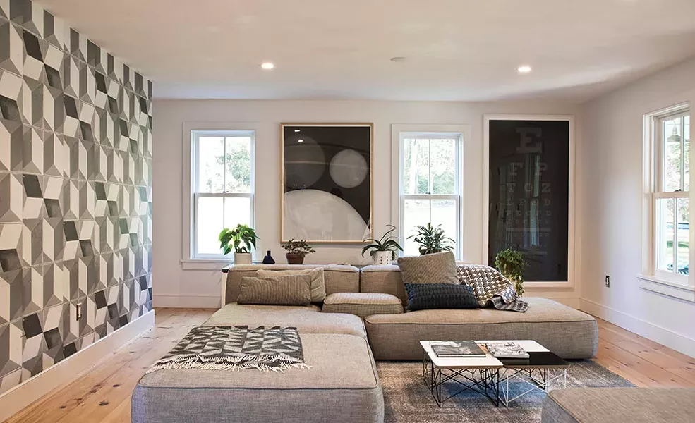 The ground level of the 20’-by-16’ addition built by Quatrefoil is used as a lounge. One wall, covered with black and white wall paper made from photographed tile and designed by Deborah Bowness, conceals a back staircase leading to the master bedroom. - DEBORAH DEGRAFFENREID