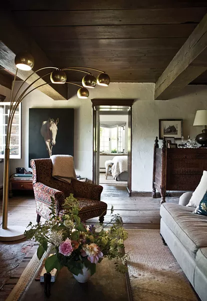 An eclectic blend of 20th-century pieces fill the home’s living room to create a space that’s both elegant and comfortable. A mid-century Italian brass floor lamp faces an Indian wedding chest in the corner of the room. A mix of sofa and chairs face the original brick fireplace, carefully repaired by a local stone mason and now in working order - DEBORAH DEGRAFFENREID