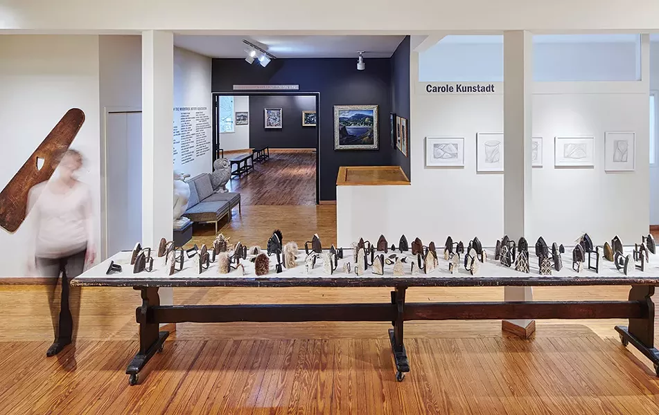 Pressing On installation, 86 antique sad irons on 16’ wooden table by Elizabeth M. Fraser (ca. 1920), Woodstock Artists Association & Museum - PHOTO BY KEVIN KUNSTADT