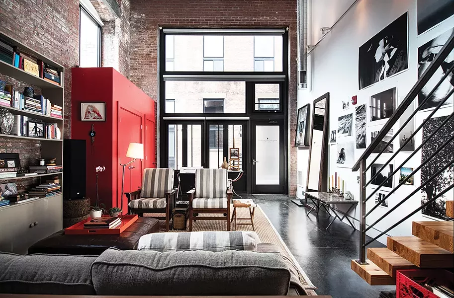 The front end of the loft is dominated by a bright red closet Rice added when she moved in. The striped grey chairs were upholstered with fabric from Sylvester & Co. in Sag Harbor, NY and paired with a cowhide bench made by Amy Pilkington. The marble coffee table in the foyer is from Maison Gerard in New York. - PHOTO: DEBORAH DEGRAFFENREID