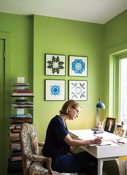 Walker sitting at her desk. The geometric paper cuttings hung above are also by local artist Jenny Lee Fowler. “A lot of what I do is help people find their own style and inspire them to be more confident with their own design decisions,” explains Walker. “Every job is completely new. It has to do with that person, their space, and who they are. I love collaborating and find myself appreciating someone else’s idea that at first I might have disagreed with. That’s the fun part.” - PHOTO: DEBORAH DEGRAFFENREID