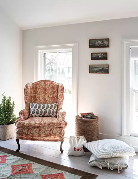 A sitting area makes up a cozy corner of the - home’s master bedroom. “I love pattern, and I’ve always collected textiles,” she explains. She bought the triptych photo of a mountain range hung above the chair from a thrift store in Brooklyn. - PHOTO: DEBORAH DEGRAFFENREID