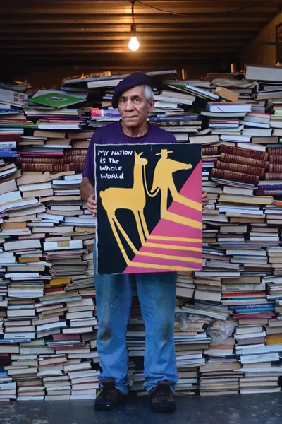 Martin Muñoz with one of his paintings and part of his book collection. - PHOTO: OTTO OHLE