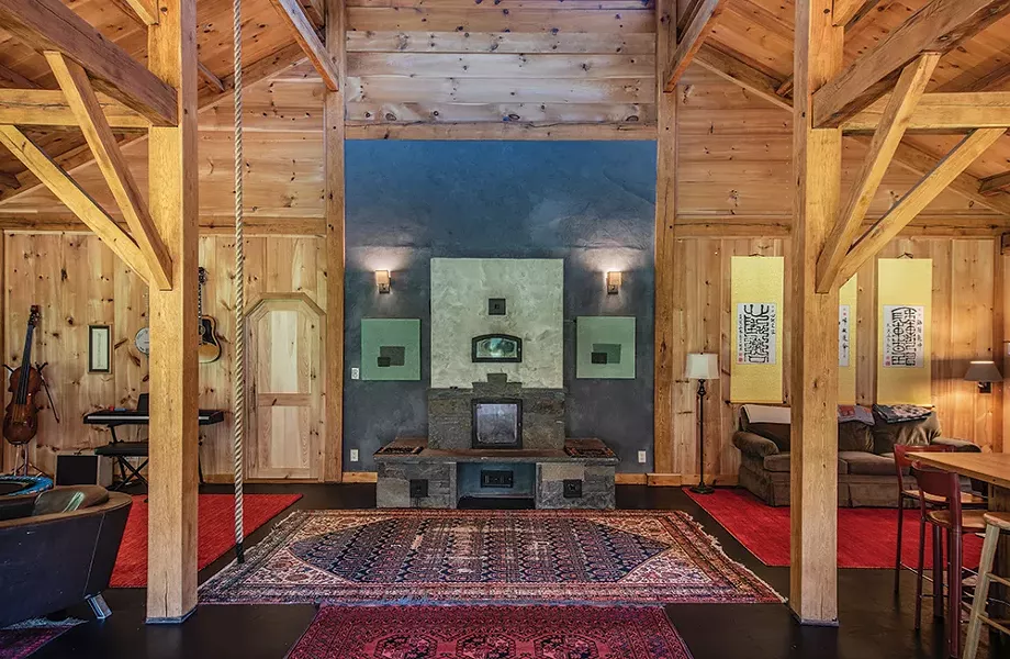 The home’s large main room—with dining and living areas and the kitchen—strikes a balance between family and contemplative space. A trampoline and a climbing rope hung from the ceiling are regularly utilized by Duncan and six-year-old August for exercise, and the space’s western corner is dominated by Masse’s collection of instruments. In opposing corners, two peaceful sitting areas provide views to the surrounding landscape. Duncan - designed the bluestone fireplace at the room’s center. - PHOTO: DEBORAH DEGRAFFENREID