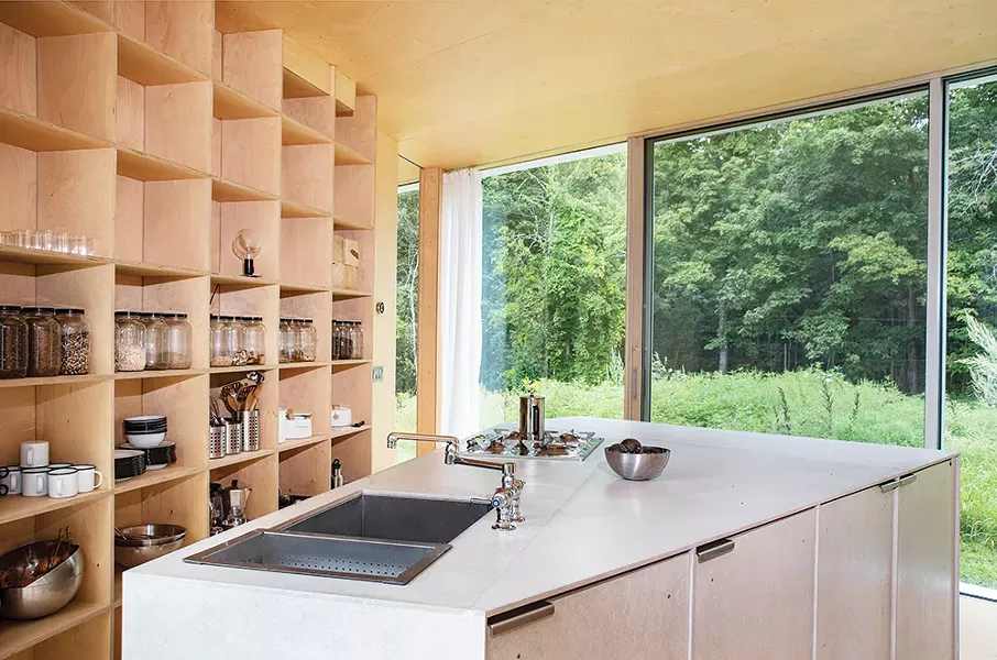 The home’s kitchen features open pantry shelving and a large island with incorporated appliances. The sections of the home are separated by pocket doors—a design feature well thought through. “It seems mundane,” Leven says, “but it really impacts the way we experience the space. Swing doors would feel very different and even obstructionist here.” - PHOTO: DEBORAH DEGRAFFENREID