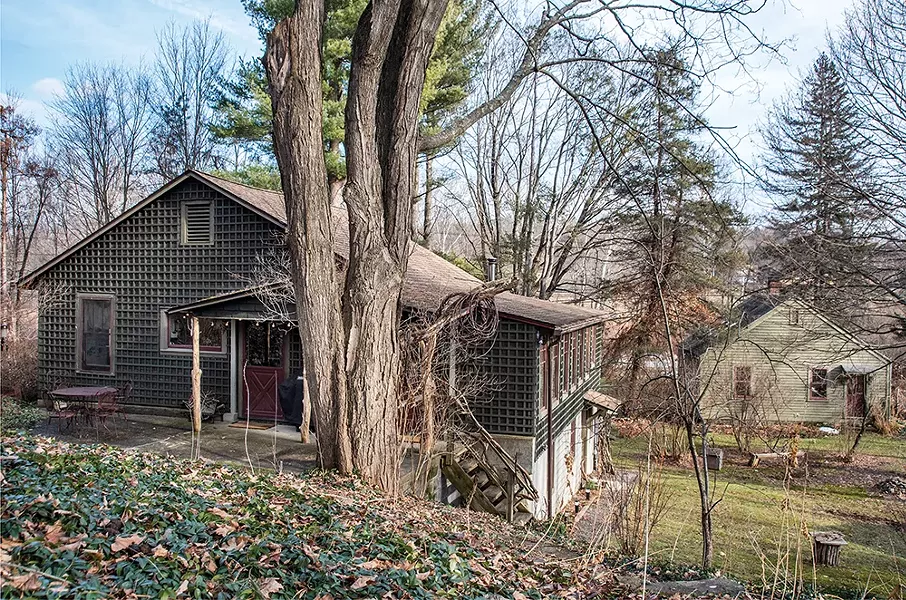 Feinberg’s one-acre property backs into a wooded hillside and was surrounded by slightly - wild but well-planted gardens, which, along with - the buildings, she eventually brought back to life. - “I’d never gardened until I got here—that was a - revelation,” she says. In the foreground, her lattice-covered house looks out onto a private courtyard. - and an exterior staircase with a playful bannister - of twisted branches that Feinberg collected from - the property. - PHOTO: DEBORAH DEGRAFFENREID