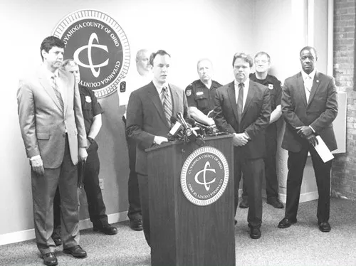 Ed FitzGerald, surrounded by county officials and safety leaders from various suburbs, announces a stricter approach to heroin investigations.