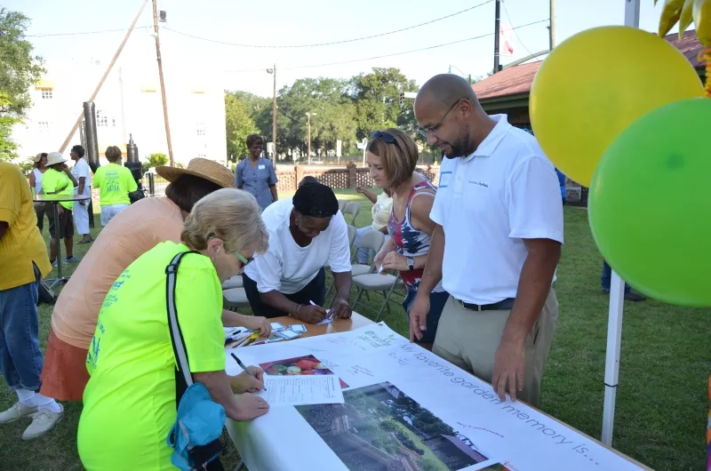 CRI Health Literacy and Research Fellow Chad Lewis (in white shirt) welcomes volunteers who “sign in” on a memento banner with their favorite garden memories. Photo by James Byous, © Canyon Ranch Institute.