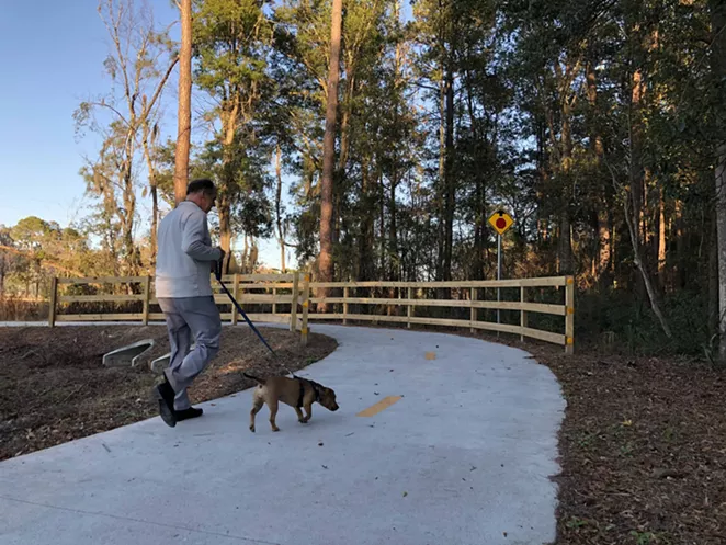A man walks his dog on the newly completed Truman Linear Park Trail. - NICK ROBERTSON/CONNECT SAVANNAH