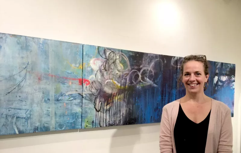 Deb Oden, painter, printmaker and co-curator of “The Industry,” stands before her contribution to the Kobo Gallery exhibition.