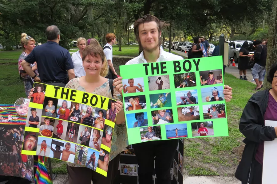 Luke Edenfield (a.k.a. The Boy) escorted by his Aunt Melanie on the first day of Senior year and holding posters filled with precious childhood memories.