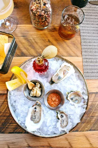 Fresh shucked oysters with an antique perfume bottle filled with house made mignonette, peanut horseradish and cocktail sauce.