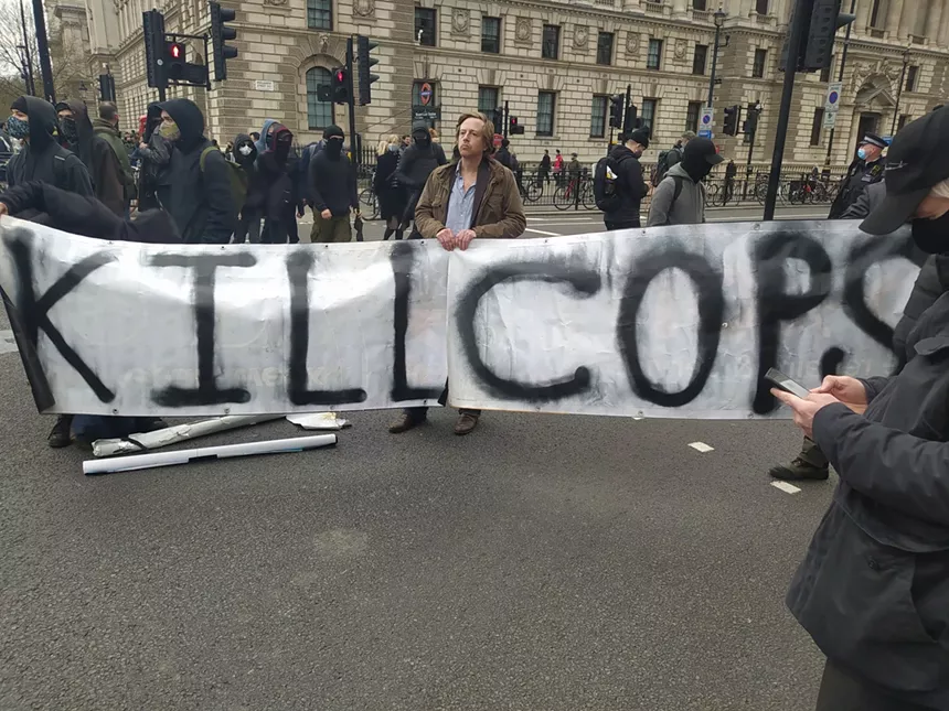 Barrett Brown holds the "Kill Cops" sign at a London protest against a new crime bill. - ANDY NGO VIA TWITTER