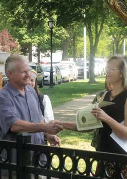 At the dedication ceremony, Springfield Mayor Mike Houston presents Sandy Baksys, organizer of the marker project, with the city proclamation announcing “Lithuanian-American Day.” - PHOTO BY WILLIAM FURRY
