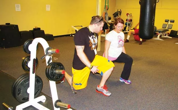 Personal trainer Cole Endres demonstrates for Stephanie Templeton proper technique for the lunge, an important bodyweight exercise. - PHOTO BY JOSEPH COPLEY