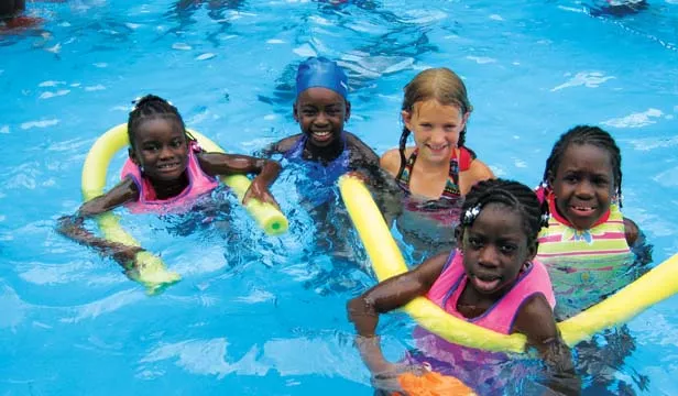 Raegan Koebler, center, got acquainted with children adopted from Haiti at a camp in southern Indiana in July. She is raising money to rebuild a destroyed orphanage in Haiti. - PHOTO BY DINA KOEBLER