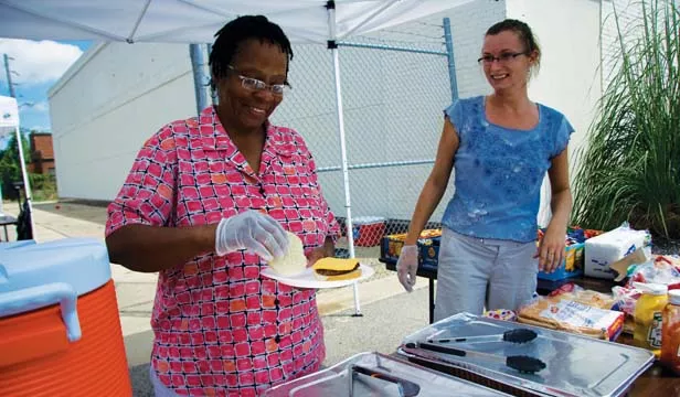 CCHC patient and board member Racine Freeman serves food during the center’s celebration of National Health Center Week. - PHOTO BY PATRICK YEAGLE