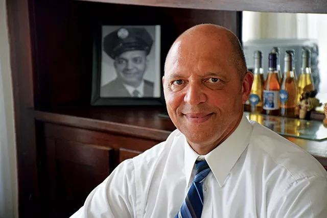 Herman Senor poses in his childhood home in Springfield by a portrait of his father, Clarence L. Senor.