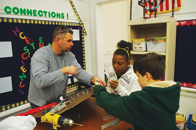 Crawford, Murphy & Tilly engineer Jim Michael works with Dan Hartman’s students Kenadie Butler and Colin Furkin on their Rube’s plinko board.