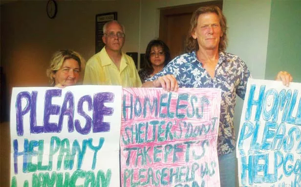Karen Otterson (left) and Don Norton (right) hold signs used by panhandlers at a July 2 Springfield City Council meeting. The pair sued the city this week in a federal class action lawsuit over the city’s anti-panhandling ordinance. - PHOTO BY PATRICK YEAGLE