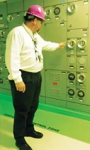 Stovall points out the two-foot green border on the floor surrounding electrical equipment, which lets employees know where they can and can’t walk without risk of electrical shock. - PHOTO BY DIANE IVEY