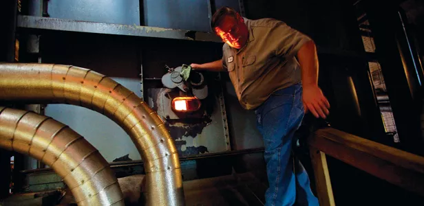 Light and heat from the No. 3 boiler illuminates Kevin Wetter, the assistant chief engineer. Temperatures inside the boiler are 1,200-1,300F. - PHOTO BY JONATHAN KIRSHNER