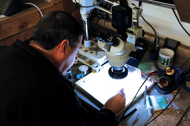 (Left) Brian Dickerson gives a demo on how the micro soldering station is used to fix processors (right). BLH is one of the only companies from Chicago to St. Louis that can repair damaged cellphone components. - PHOTO BY BRANDON TURLEY