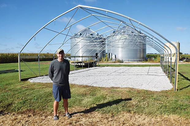 Hilltop Community Garden Field Manager Kyl Reed and the "hoop house" under construction where seedlings and produce can be raised over the winter months. - PHOTO BY DAVID BLANCHETTE