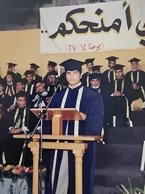 Nabih Elhajj delivering high school commencement address at Sacred-Heart Beirut, 2005. The banner in the background, written in Arabic, quotes John 14:27: “Peace I leave with you.” - PHOTO COURTESY NABIH ELHAJJ