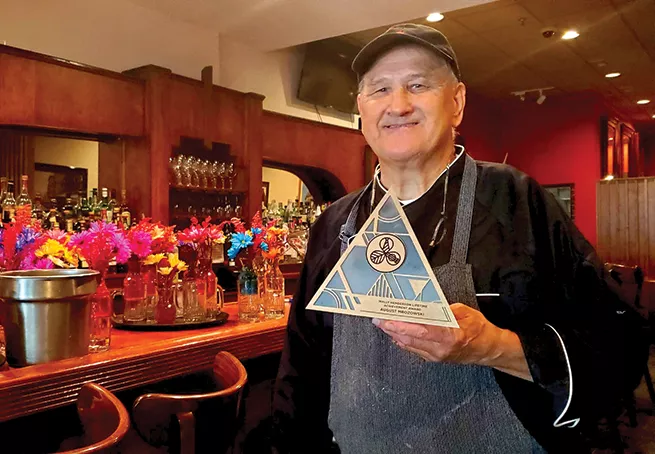 Chef Augie Mrozowski holds his lifetime achievement award near the entrance of the Front Burner on one of his last days working there. - PHOTO BY RACHEL OTWELL