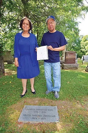 Connie McGee and Otha Davis at the Colored Section grave of their common ancestor, Leanna Donnegan Knox. They hold a copy of the 1847 document that declares Leanna to be a free black woman. - PHOTO BY DAVID BLANCHETTE