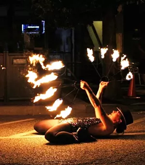 Severyn Beekman dances with fire during the Mardi Gras themed party on Adams Street on July 4. - FACEBOOK.COM/DRMRDREAMER