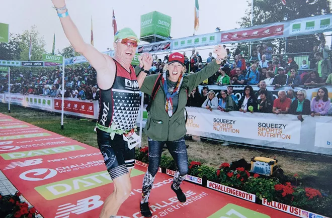 Steve O’Connor crosses the finish line at the DATEV Challenge Roth 2019 triathlon in - Roth, Germany, in July 2019, joined by - his wife, Carol.