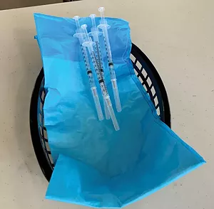 Shots of the Pfizer/BioNTech COVID-19 vaccine sit on a table at the Illinois State Fairgrounds mass vaccination site. - PHOTO BY MARY HANSEN