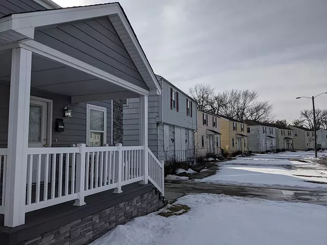 A model home, left, built by a developer whose plans to rejuvenate Poplar Place stands in contrast to boarded-up duplexes that dominate the neighborhood. - PHOTO BY BRUCE RUSHTON
