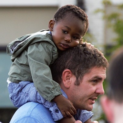 Child resting on his father's shoulders at Capital Street Dock Concert in Lewiston, July 2016. Photographed by Mary Hayward of Clarkston.