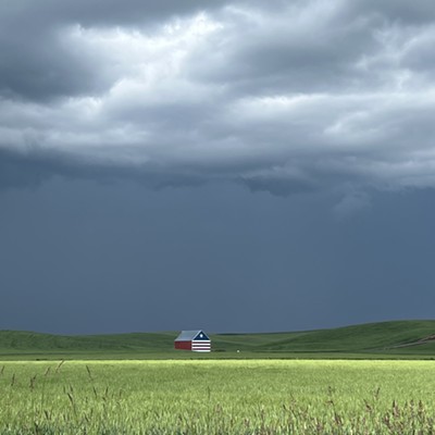 The red white and blue barn on Old Highway 95 set against the backdrop of a thunderstorm.