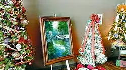 A painting by Vickie Broeckel is shown on display among decorated trees. They are part of the Festival of Trees and Art at the Center at the Whitman County Library in Colfax.