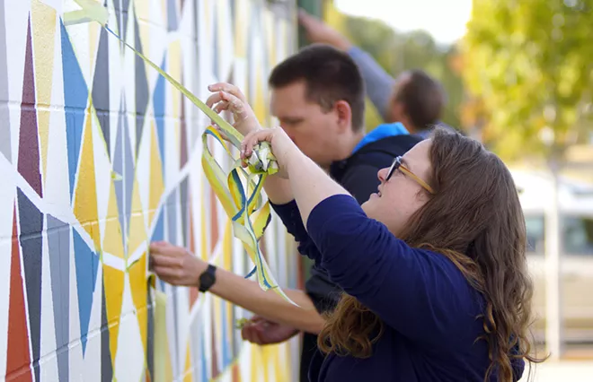 Taylor Ransom removes tape from a new mural on the side of the Art and Architecture East building Thursday afternon. The mural was designed by University of Idaho student Danielle Cappelli. - KAI EISELEIN