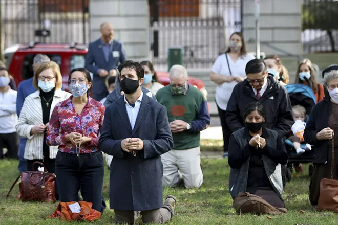 The faithful kneel to pray a rosary in the North Park Blocks during a rosary and exorcism for peace and justice in the city led by Archbishop Alexander Sample on Oct. 17, 2020, in Portland, Ore. In popular culture, exorcism often serves as a plot device in chilling films about demonic possession. Recently, two Roman Catholic archbishops showed a different face of exorcism. They performed the rite in well-attended outdoor ceremonies to drive out any evil spirits lingering after acrimonious protests. In Portland, Oregon, Archbishop Alexander Sample led a procession of more than 200 people to a city park, then conducted an exorcism rite. The event followed more than four months of racial-justice protests in Portland. - ED LANGLOIS/CATHOLIC SENTINEL VIA AP