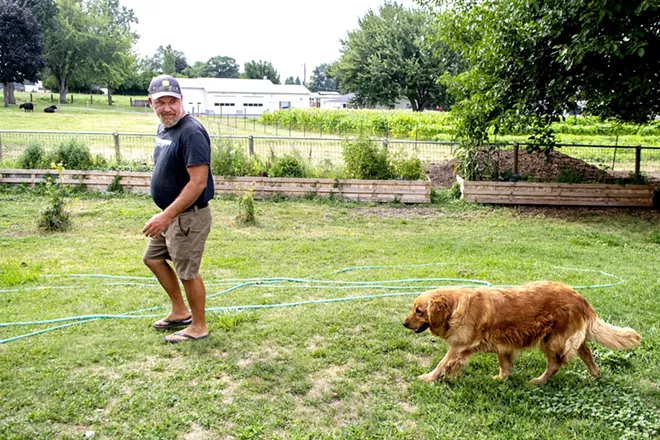 Wes Barnes makes his way towards the barn followed closely behind by the families golden retriever Rogue at their home and farm on Saturday. August Frank/Tribune - AUGUST FRANK/TRIBUNE
