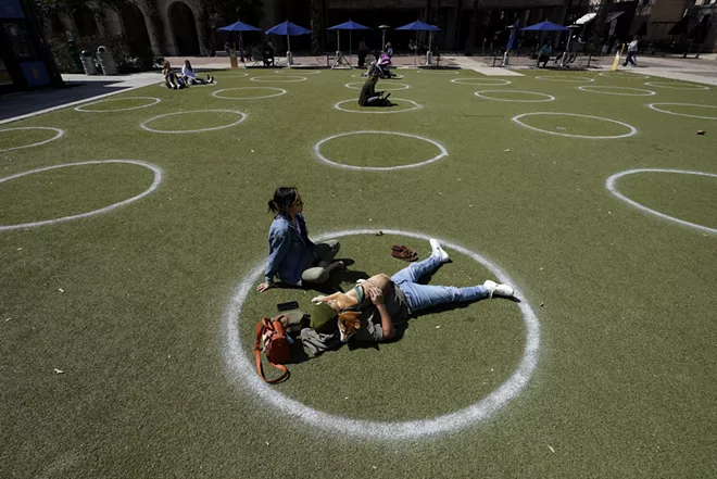 FILE - In this March 3, 2021, file photo, Kyree Kayoshi, his dog Kumi, and Miranda De Llano use circles marked for social distancing to help battle the COVID-19 virus as they relax at the Pearl Brewery in San Antonio. - AP PHOTO/ERIC GAY, FILE