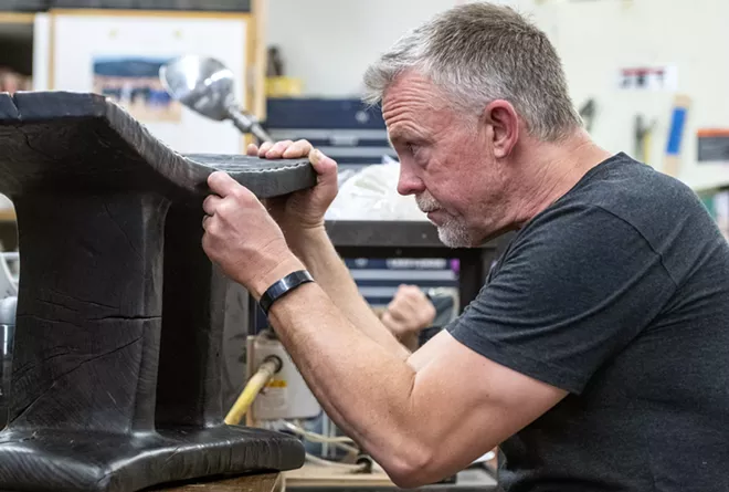 Virgil Aurand observes the grooves on a piece he calls “Elm Bench,” which was carved from a single log and then burned in a traditional Japanese style of preserving wood known as Shou Sugi Ban. - ZACH WILKINSON/360