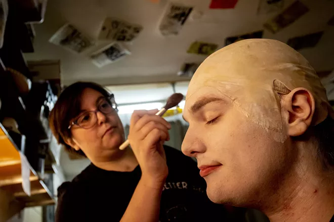 Gabi Segren applies makeup to Aven Sparkman, playing Uncle Fester, before a rehearsal for the Addams Family at the old Lewiston High School on Monday evening. - AUGUST FRANK/360