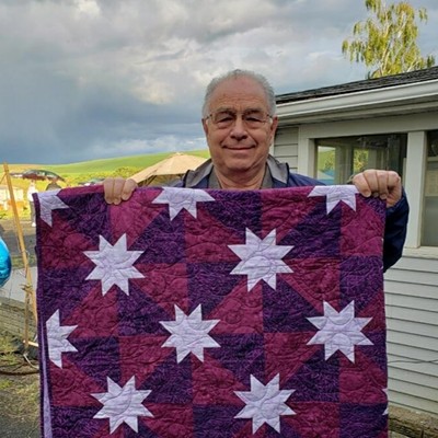 Gary Clausen of Lewiston/Clarkston area is the winner of our "Ride for a Cure" rally handmade quilt. The plum color was chosen to represent all caregivers of cancer patients. His quilt was handmade and donated by Jan (Broderick) Jarue of Alaska. This photo was taken in Pullman June 8, 2019 by Julie Hawley, co-chairperson of the rally.