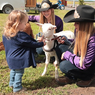 Mckenna Hodges, 2, offers a tidbit to a kid tended by Shelly McDougall and Hannah Bagby, princesses of the 2019 49ers Saddle Club. Kids and princesses were among the more than 100 to attend the 3rd annual Theon Military Flag Ceremony on May 25, to honor the fallen in service of their country. Travis Polek and Letha Brown hosted the ceremony at the site of Theon, an extinct prairie town north of Anatone, Wash. Photo by Nan Vance.